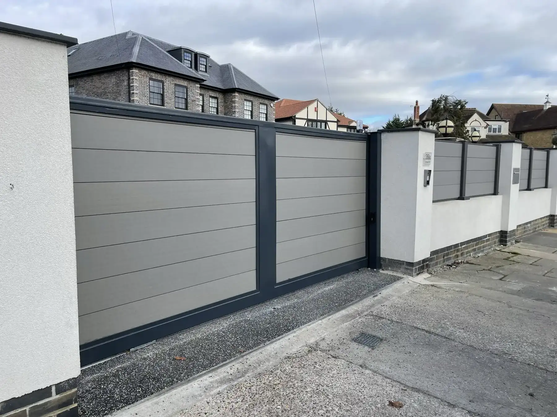 Black sliding gate in front of a red-brick home in Rayleigh